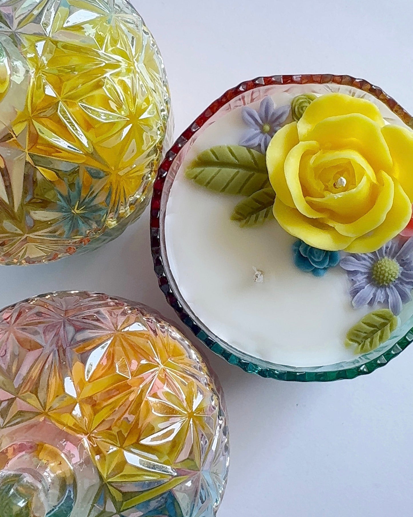 Decorative glass candle containers with floral designs on a white background