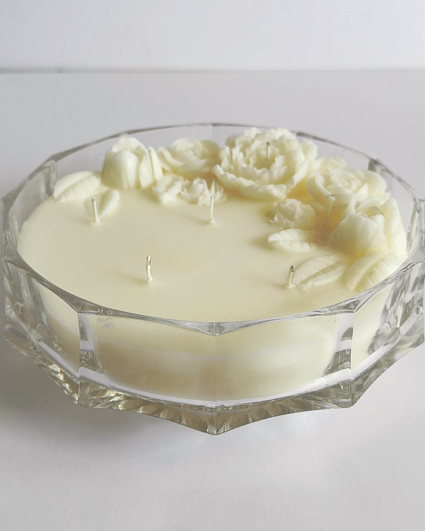 Decorative candle with floral designs in a glass holder on a white background