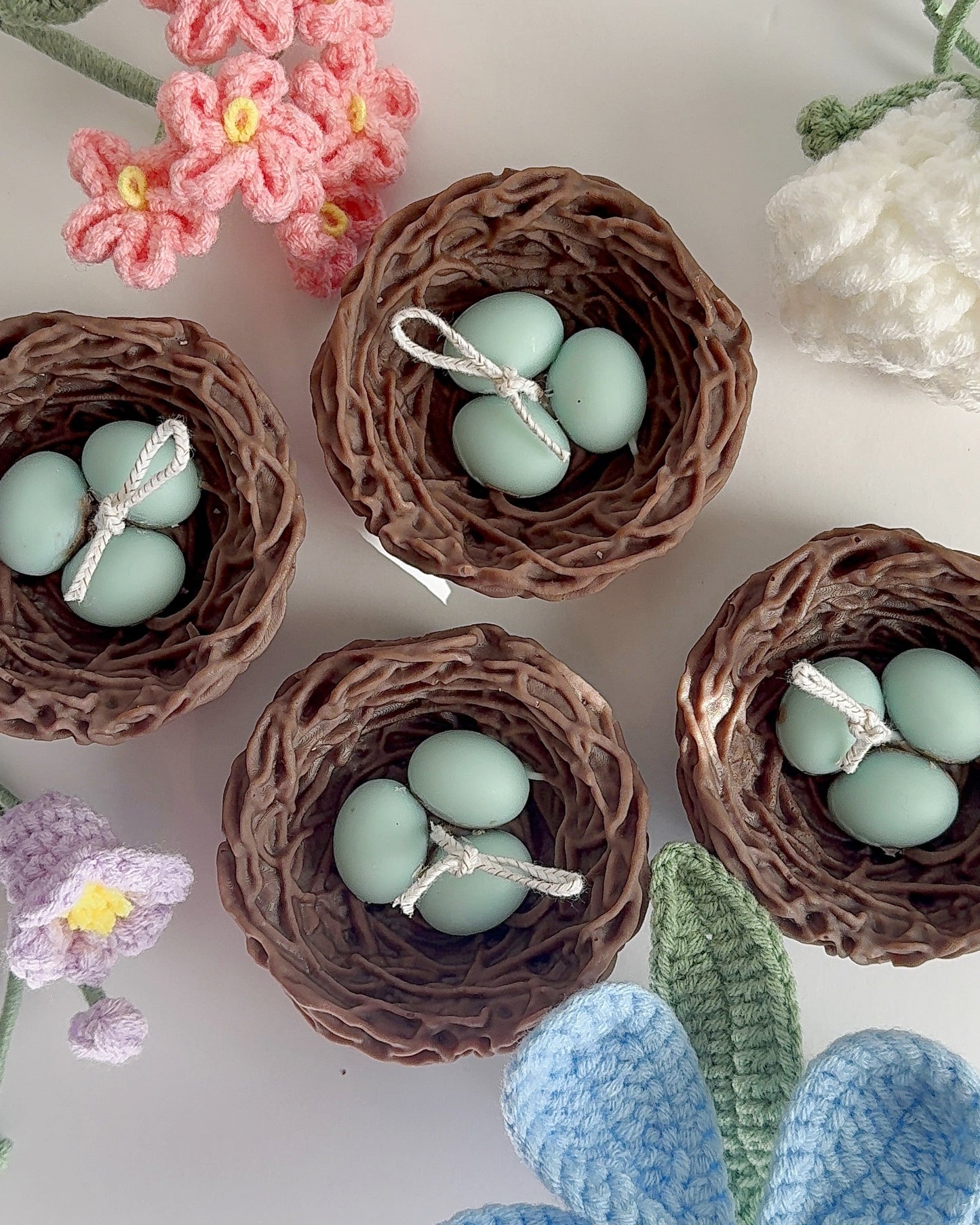 candle bird's nests with blue eggs surrounded by colorful flowers