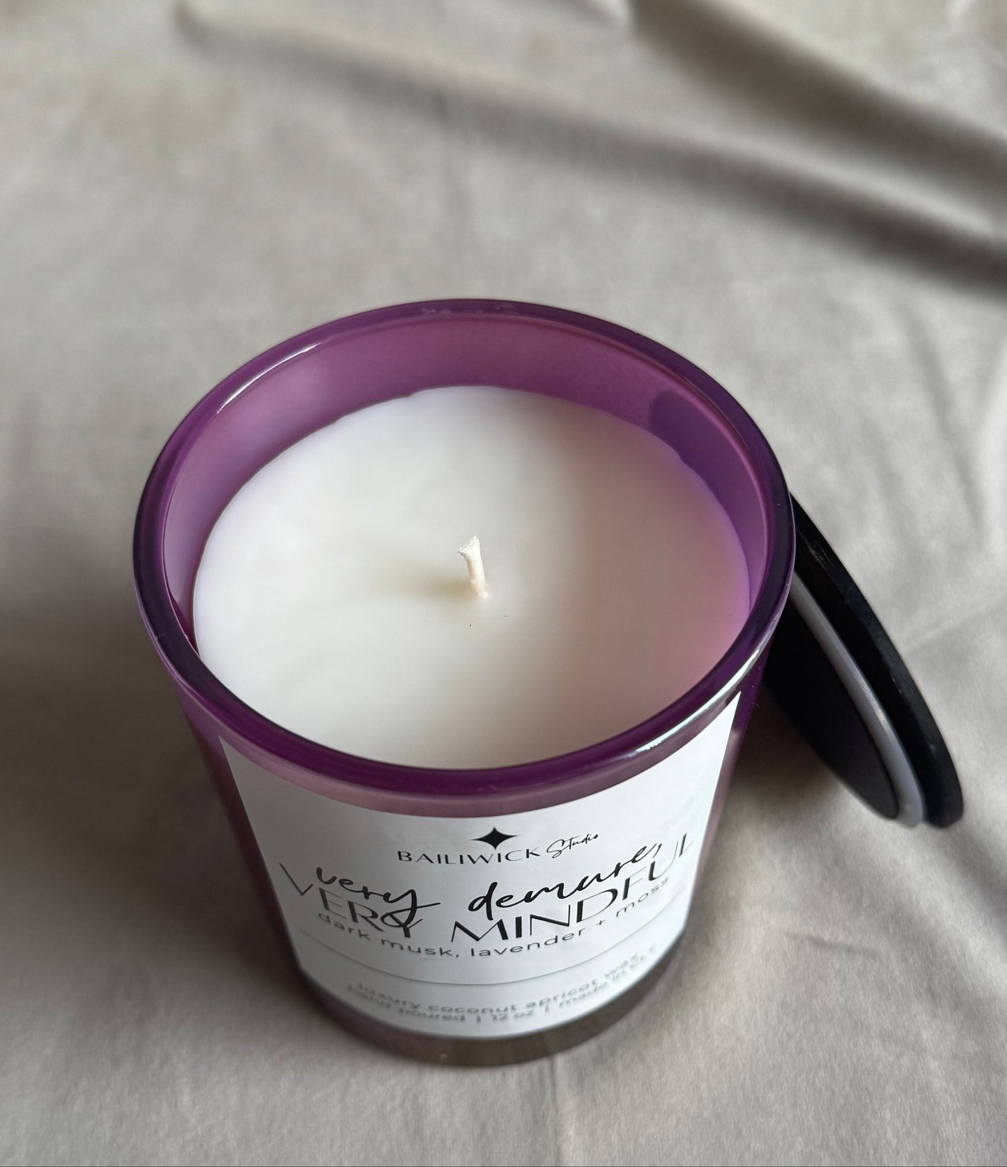 Candle in a purple container on a gray surface