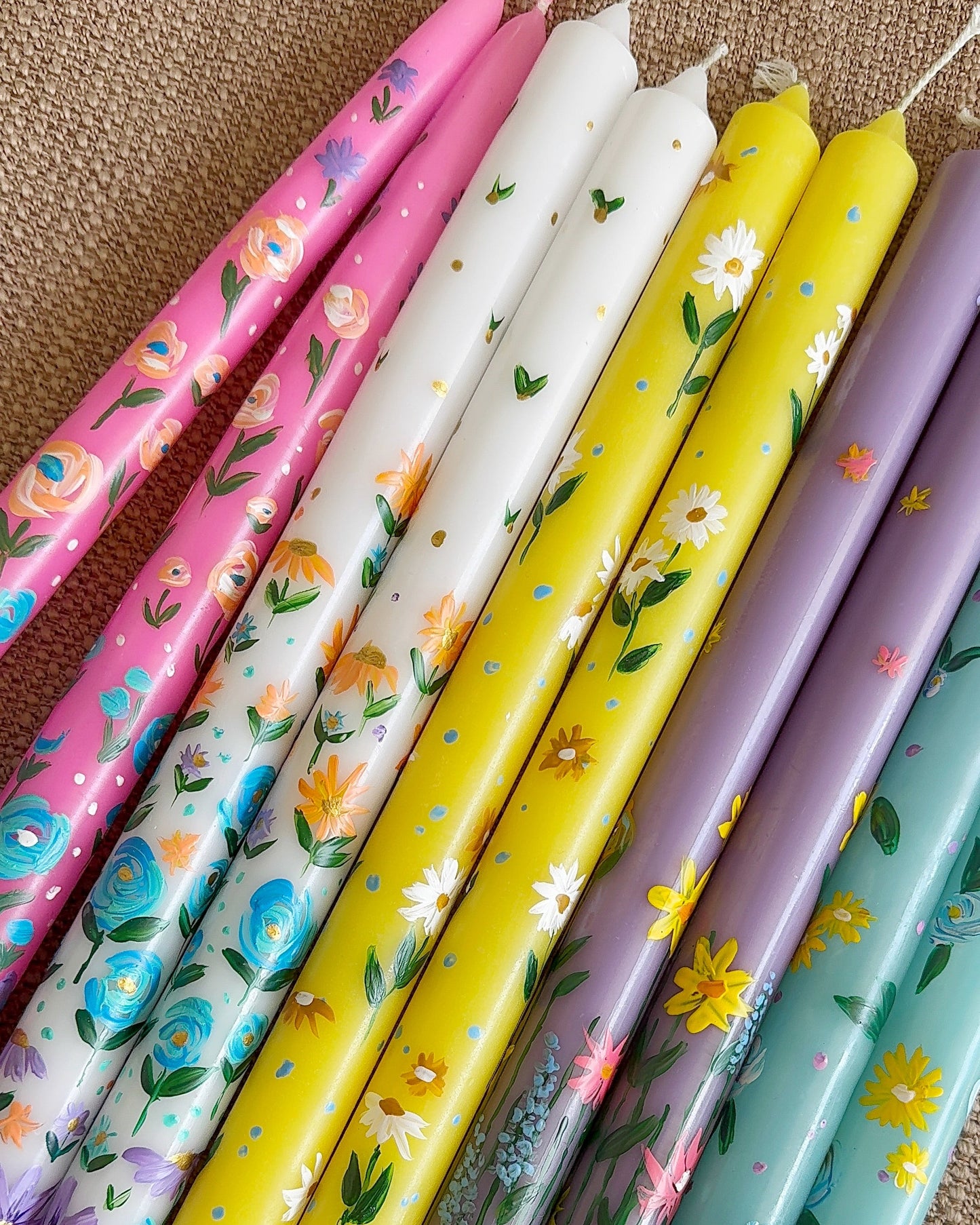Set of colorful candles with floral patterns on a textured surface