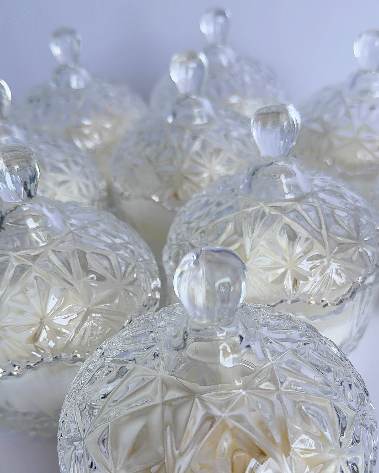 Set of clear glass candy dishes with intricate designs on a white background