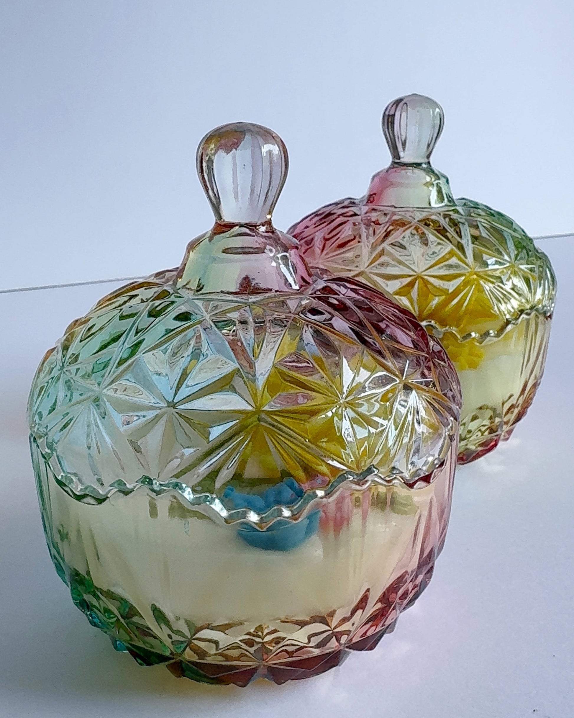 Set of colorful glass candle dishes with lids on a white background