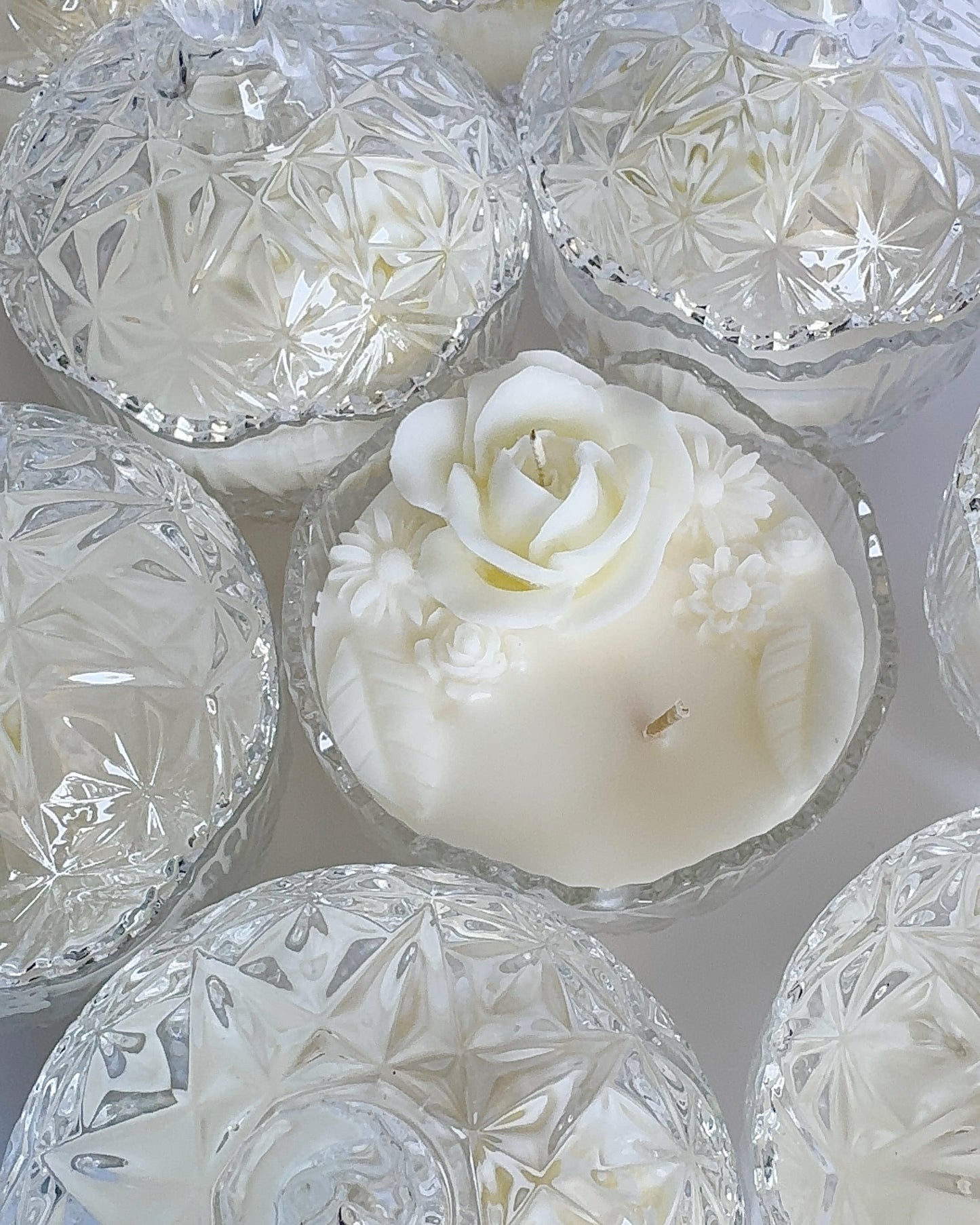 White rose-shaped candle inside a crystal dish on a white background