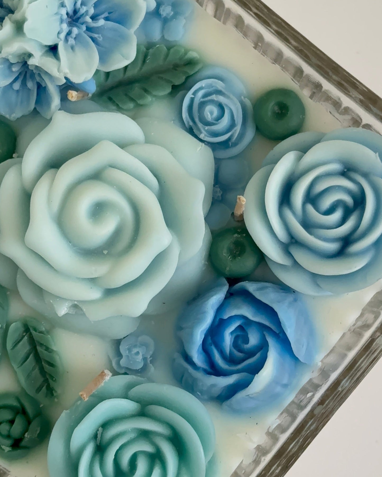 Decorative blue candle and green floral elements on a white background