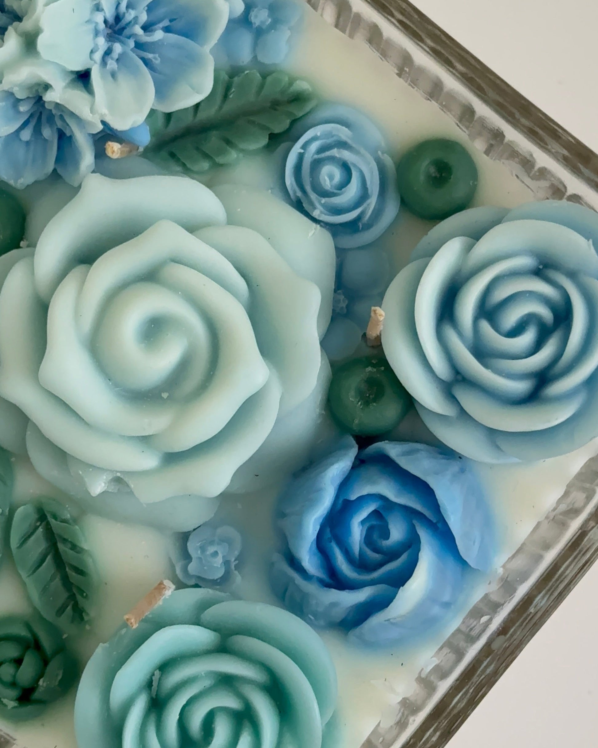 Decorative blue candle and green floral elements on a white background