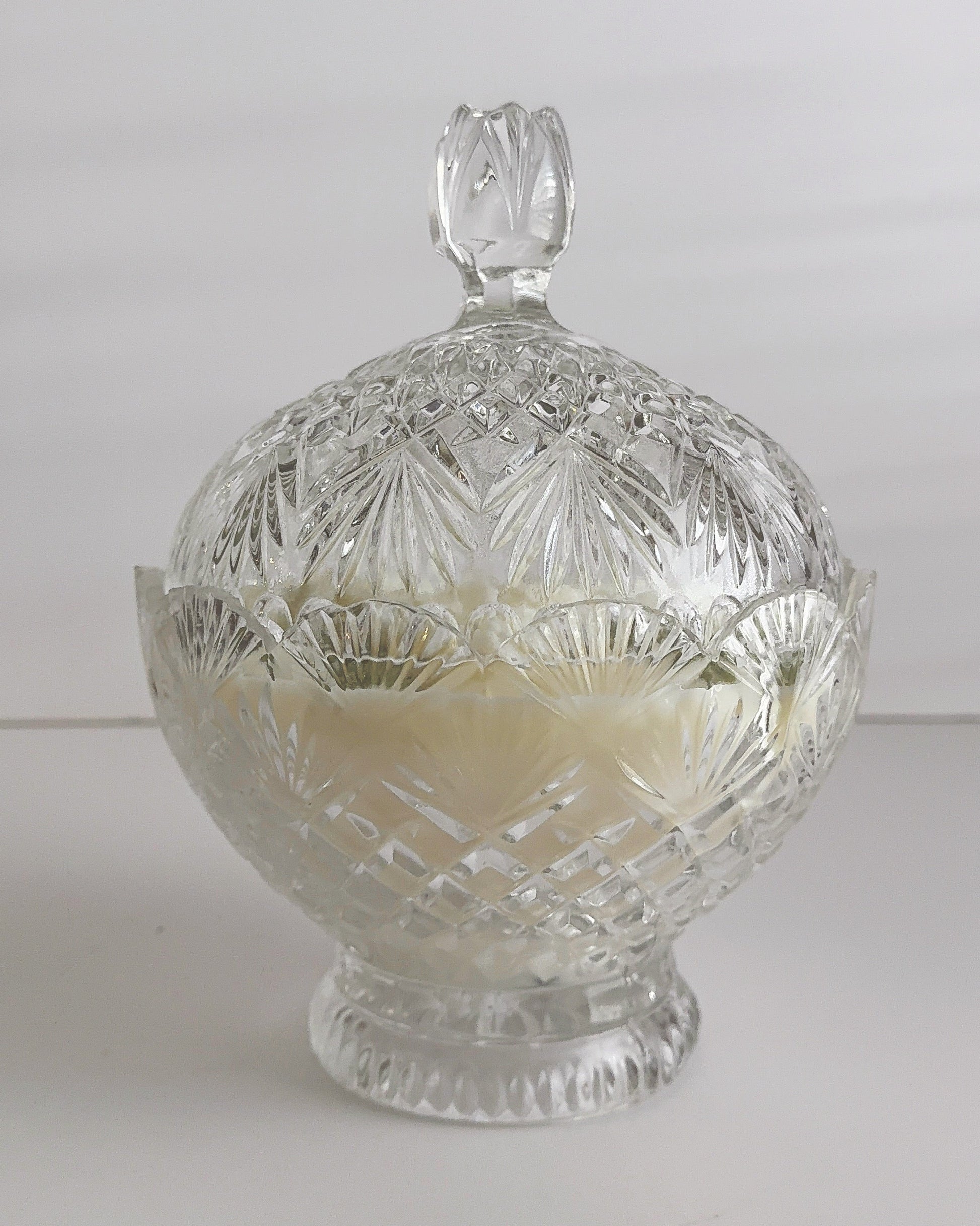 Candle poured into a Clear glass candy dish with lid on a white background