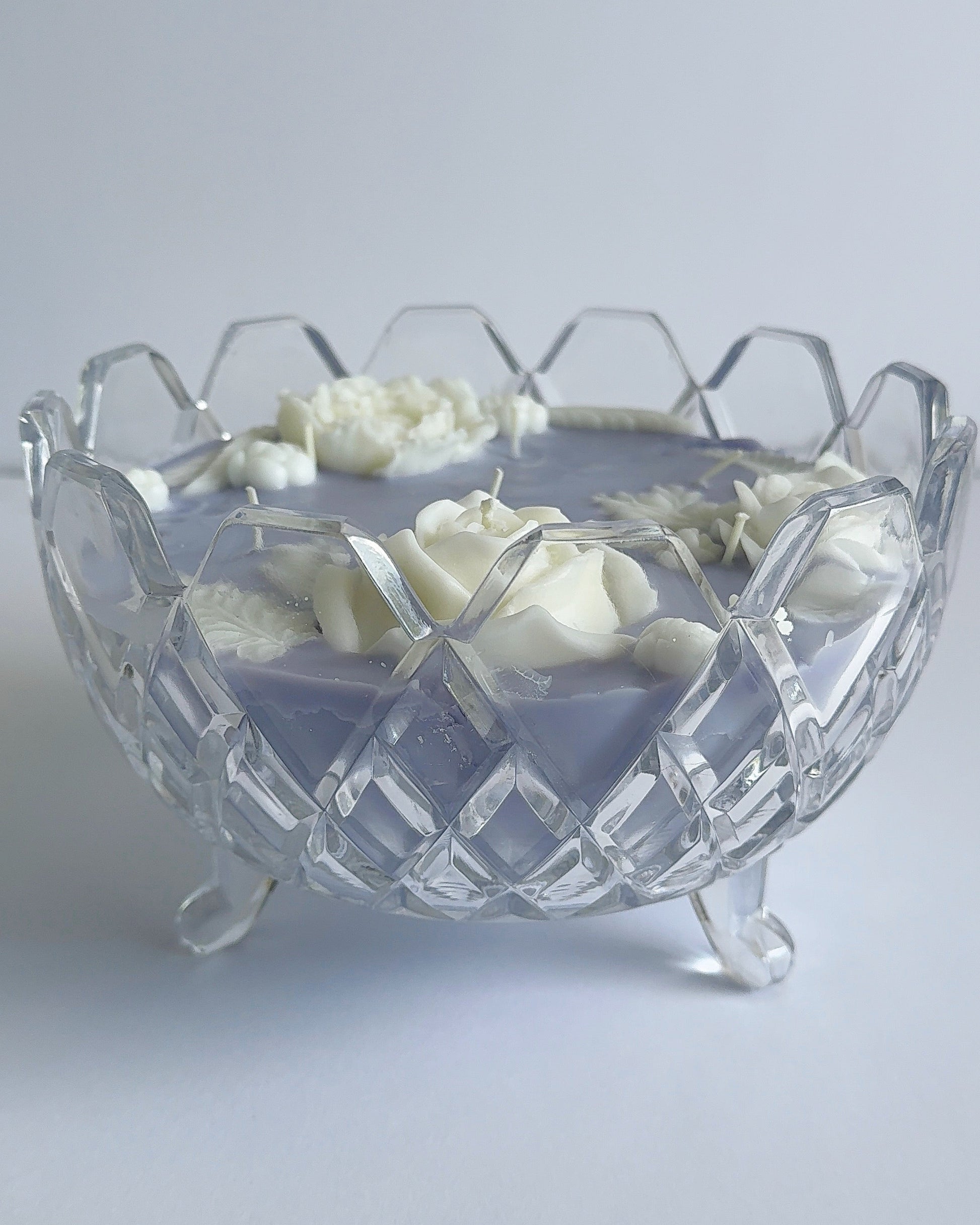 Clear glass bowl with decorative candle on a light gray background