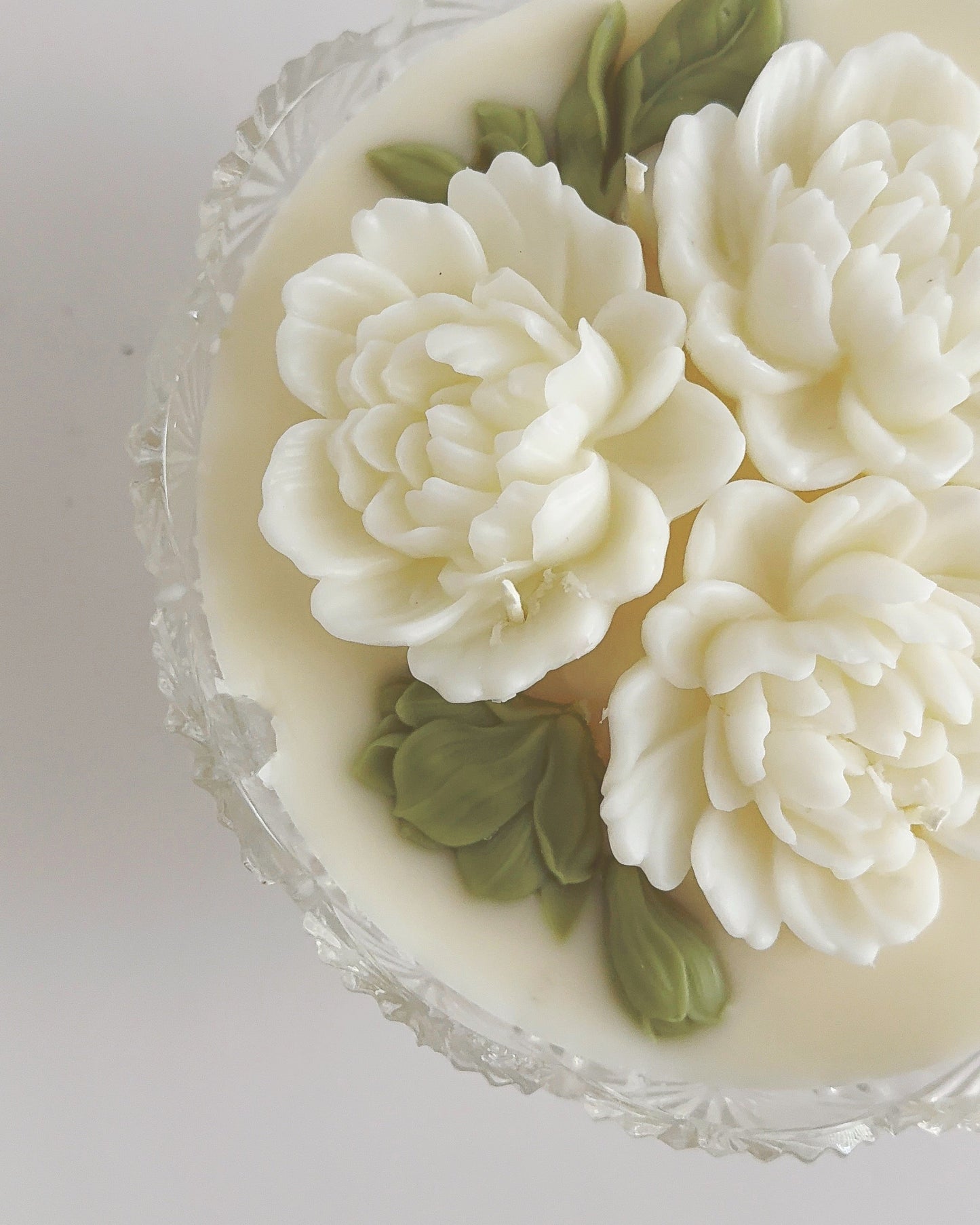 Decorative candle with floral designs on a clear glass plate