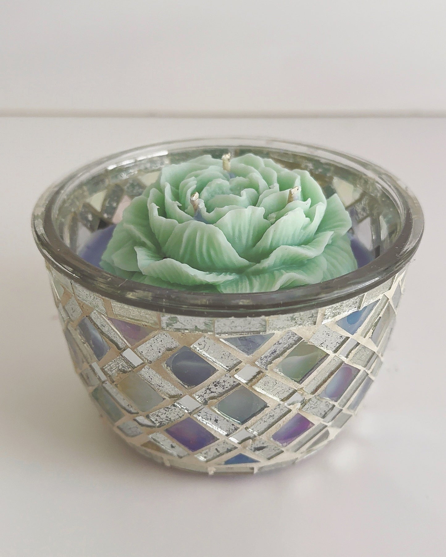 Decorative candle holder with a green candle on a white background