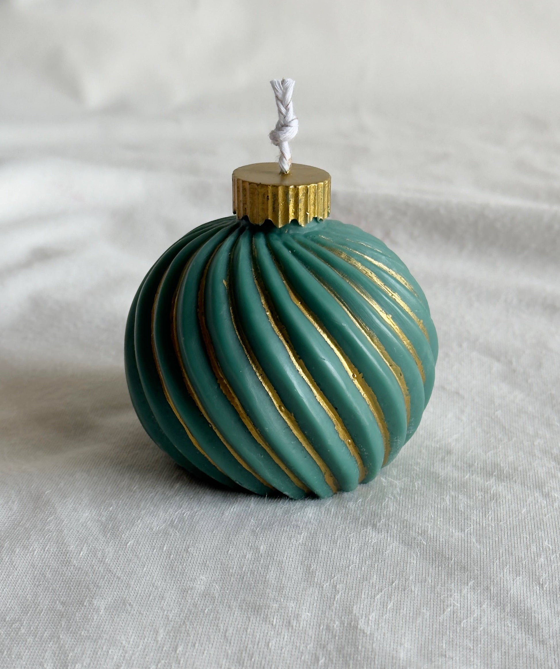 Decorative teal ornament candle with gold accents 