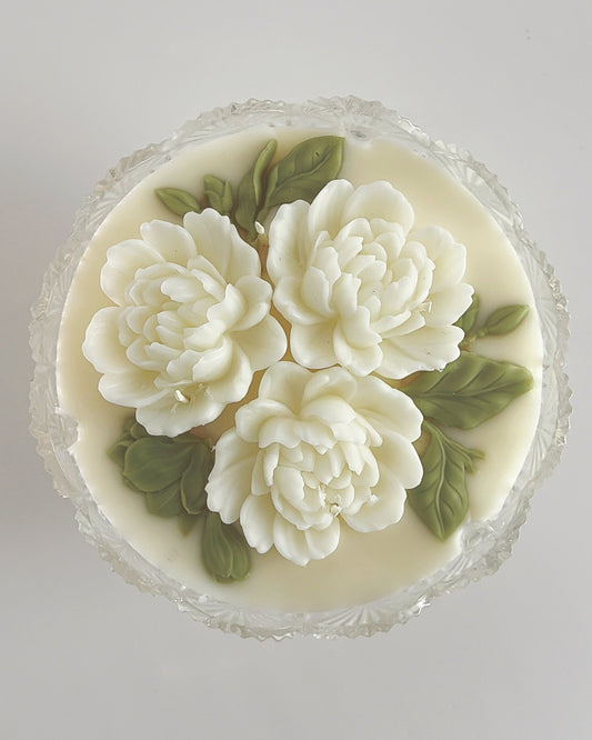 Decorative candle with white floral designs on a light gray background