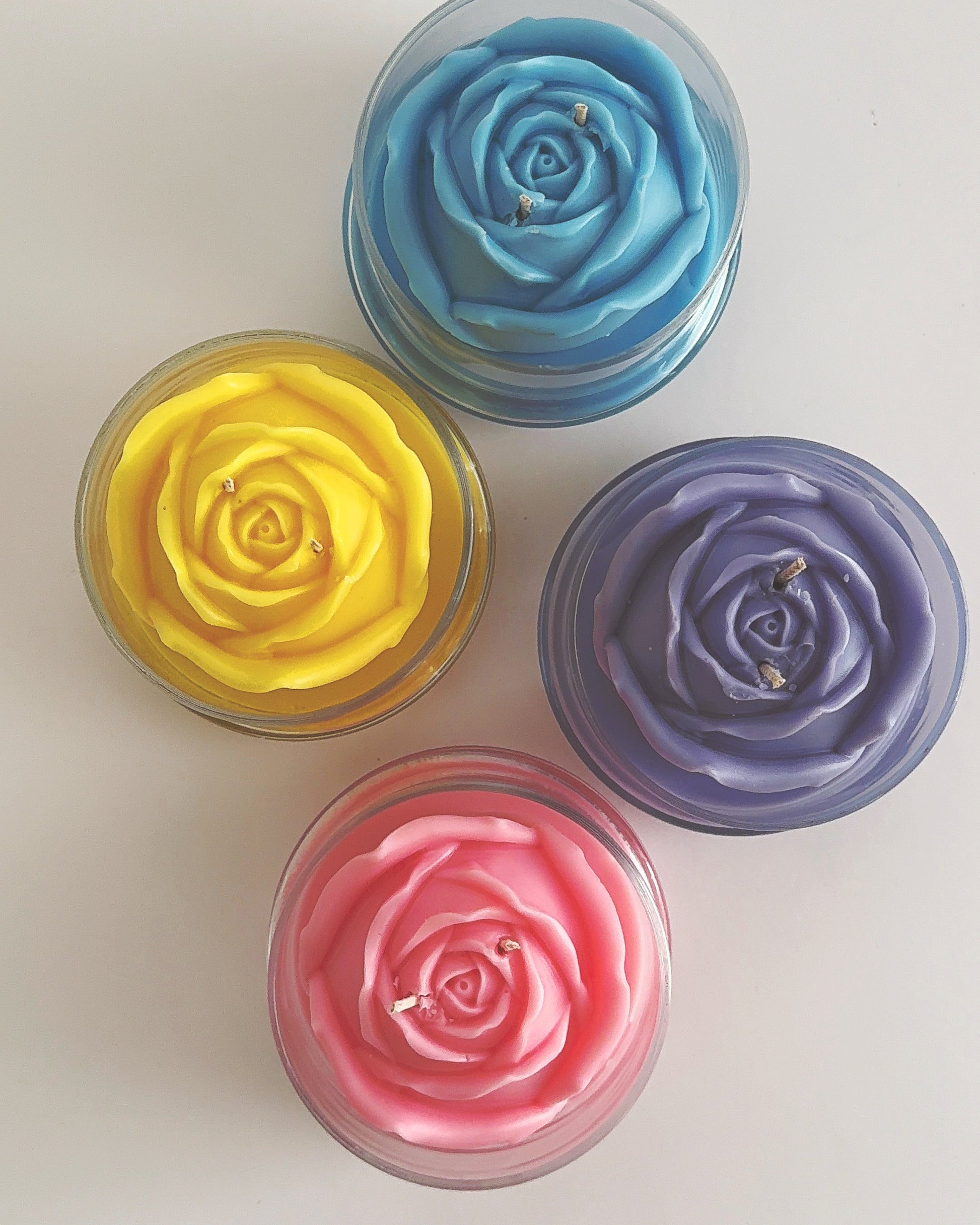 Four colorful rose-shaped candles on a white background