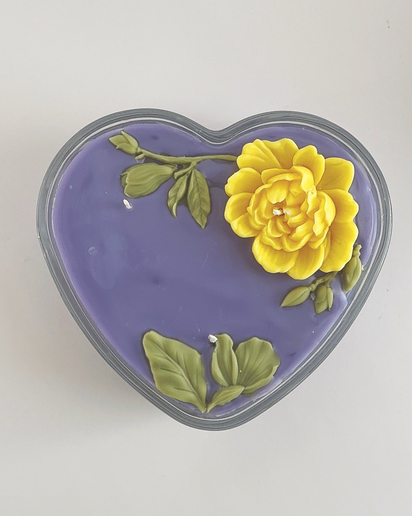 Heart-shaped purple container with a yellow flower on a white background