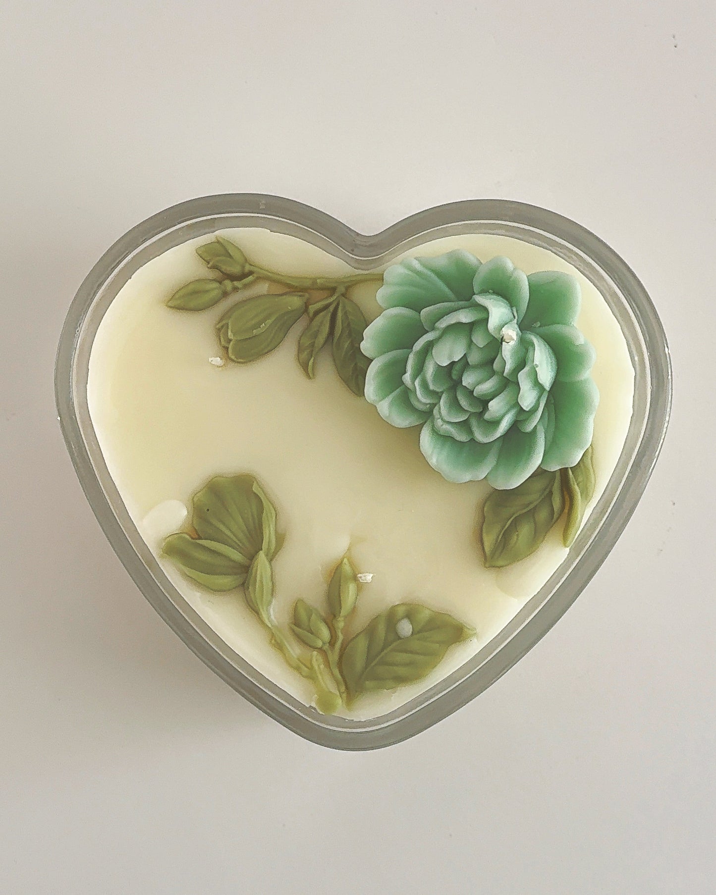 Heart-shaped soap with green succulent design on a light gray background