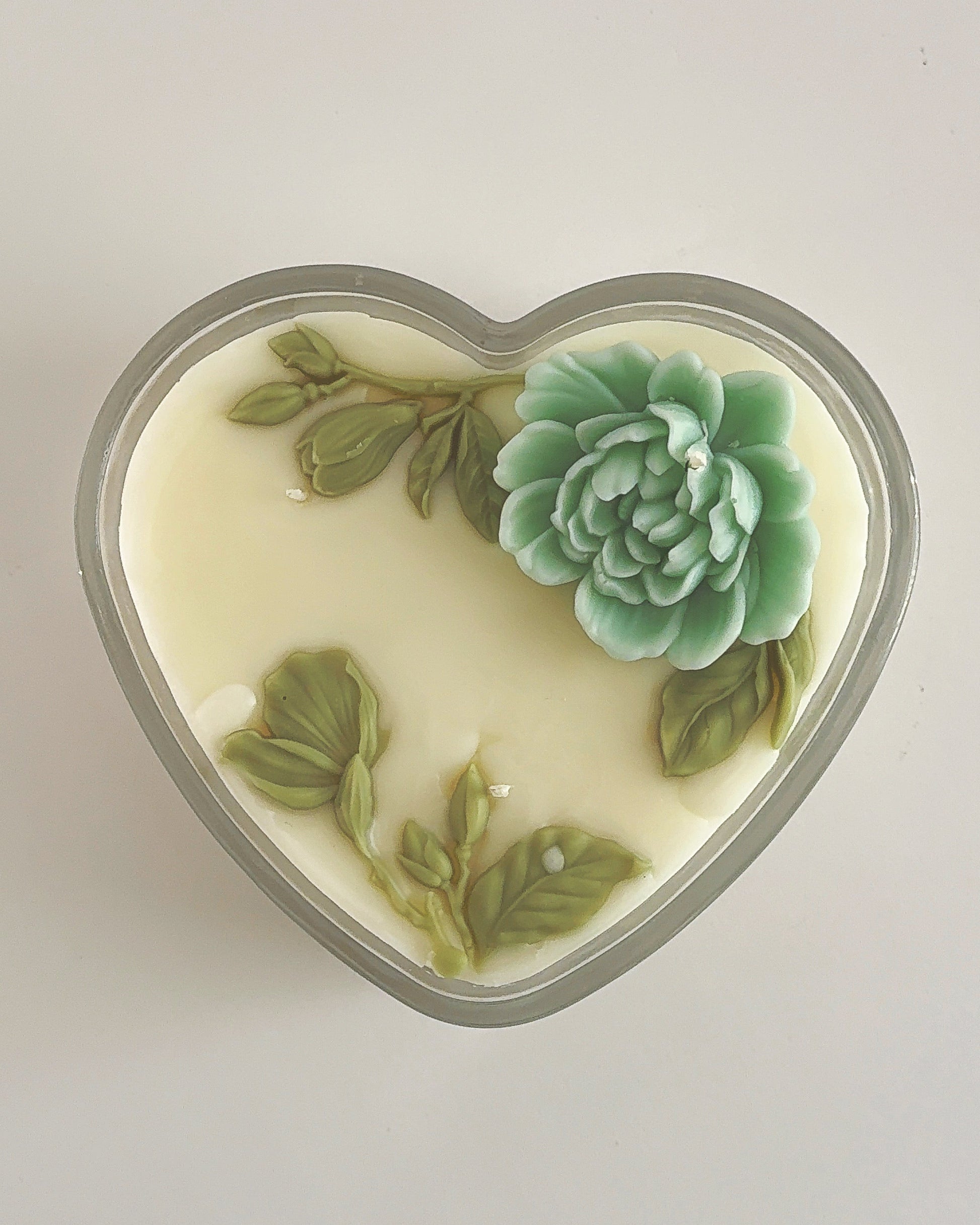 Heart-shaped soap with green succulent design on a light gray background