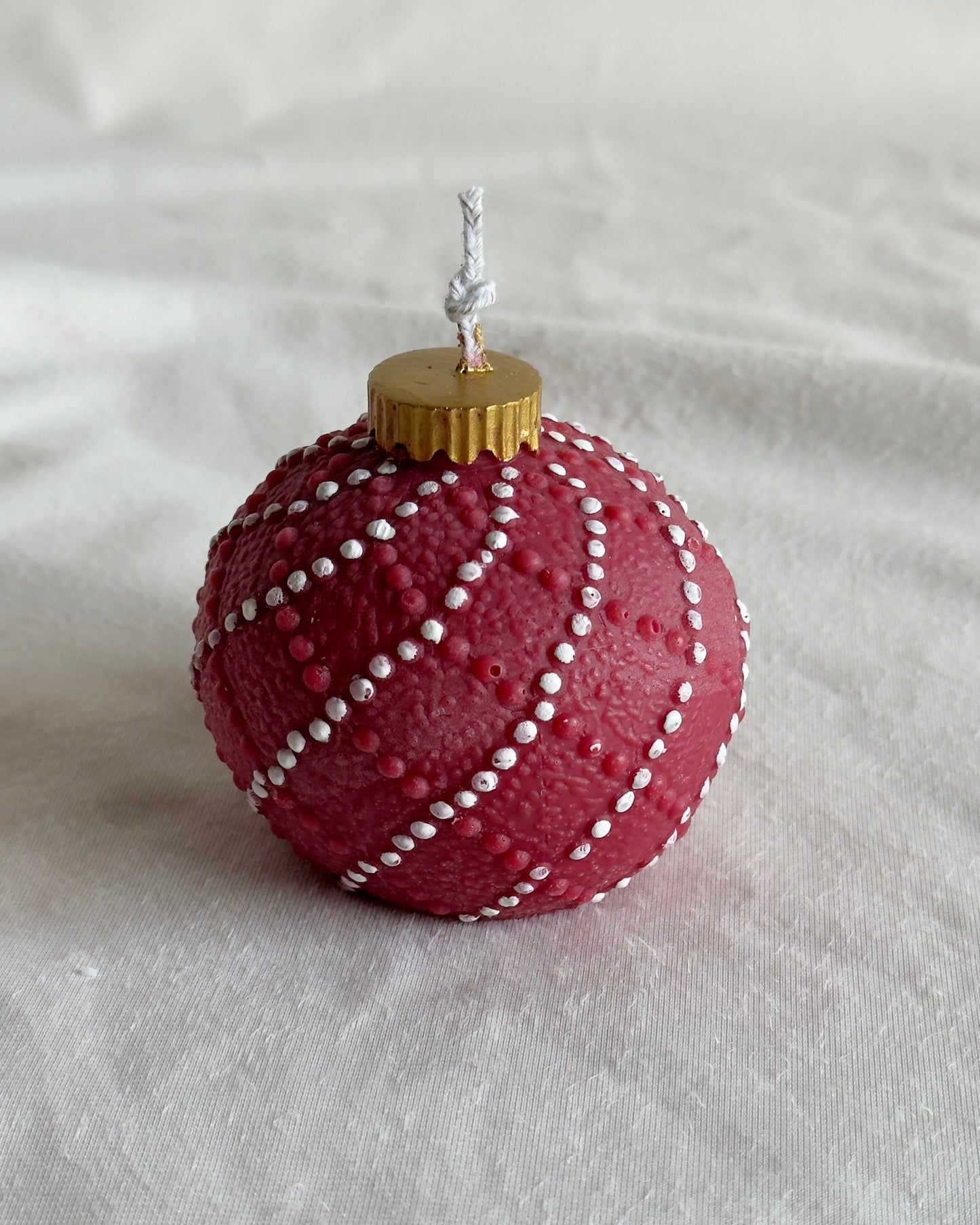 Red Christmas ornament candle with white string pattern