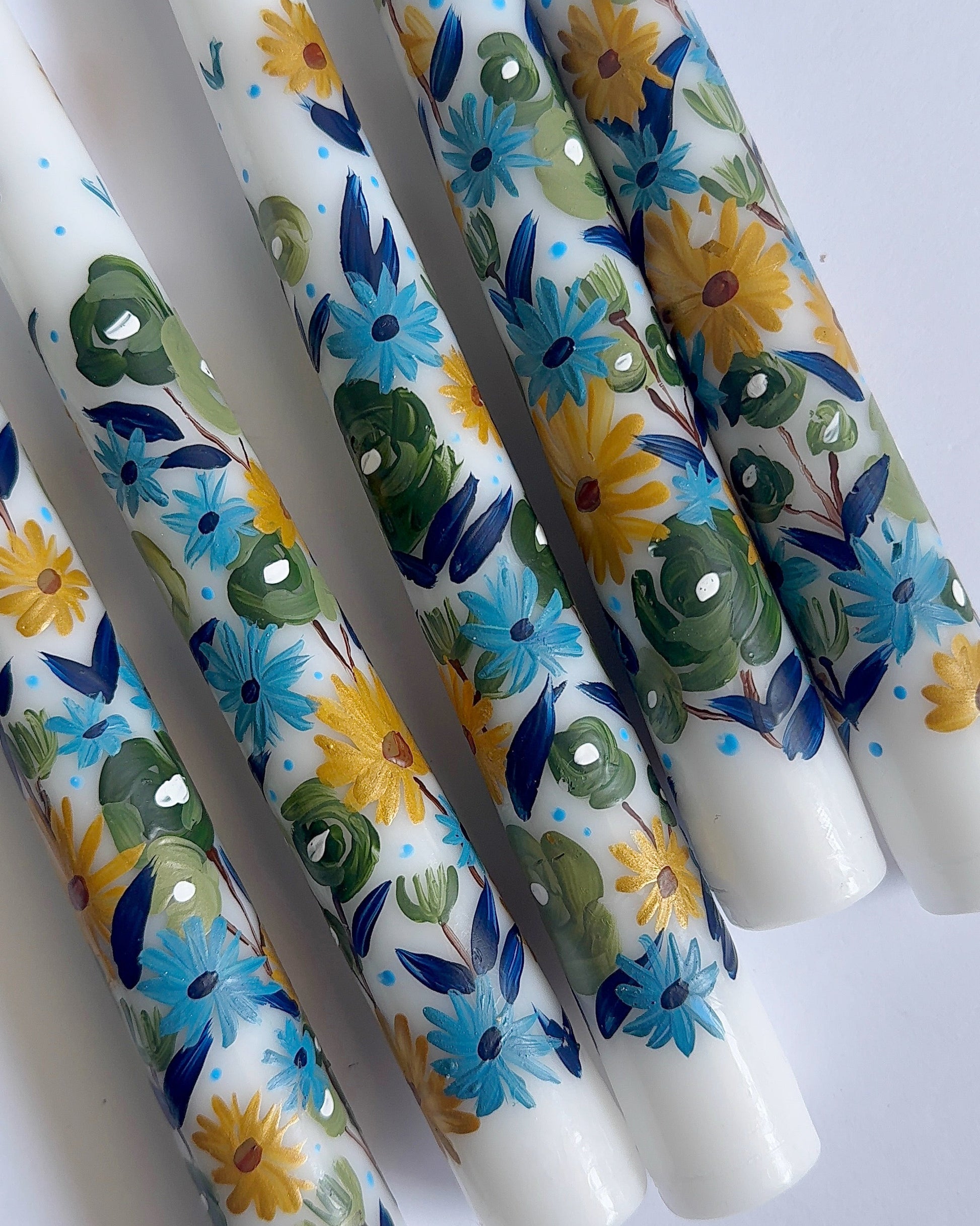 Three hand-painted taper white candles with floral designs 