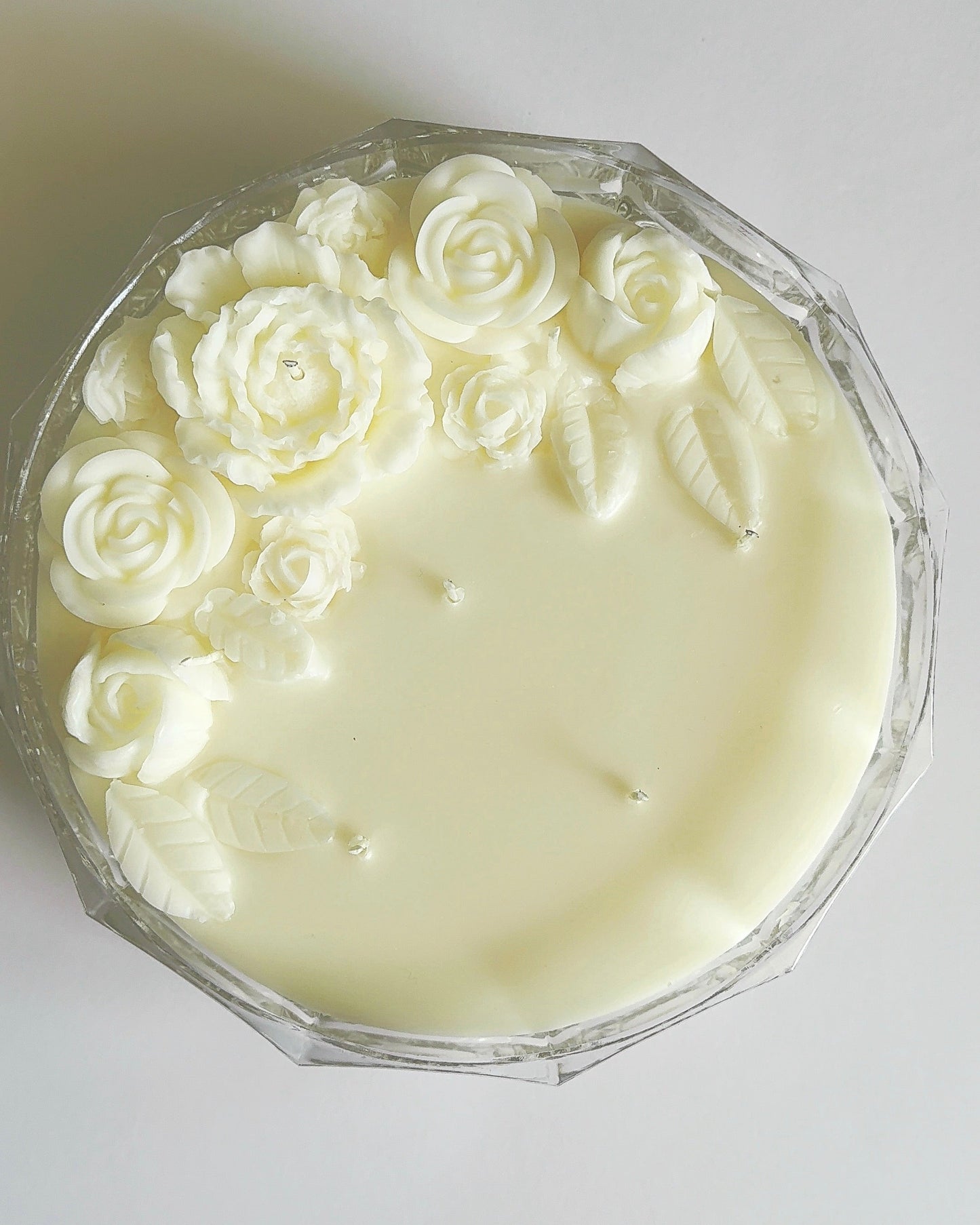 White candle with wax rose decorations on a white background