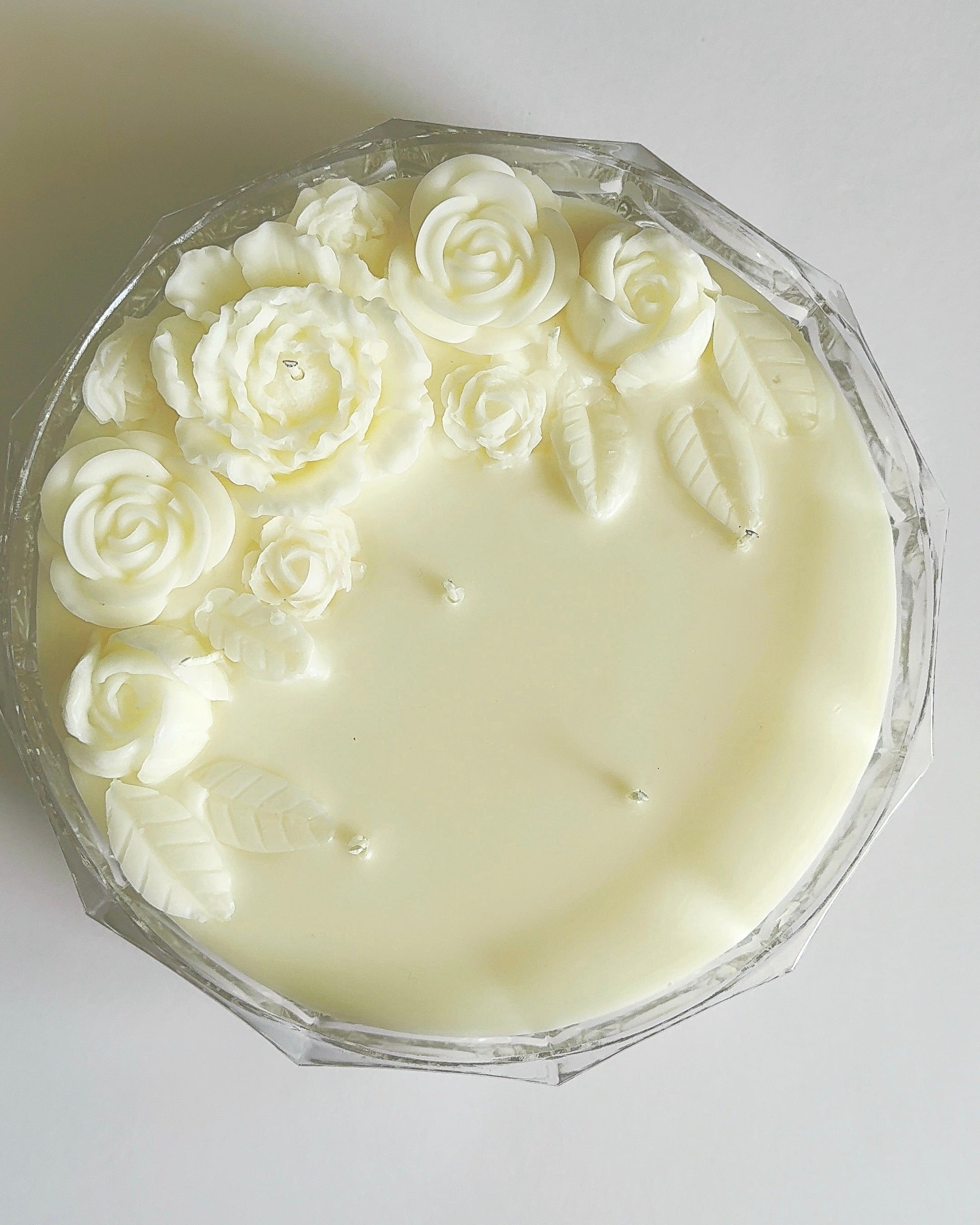 White candle with wax rose decorations on a white background