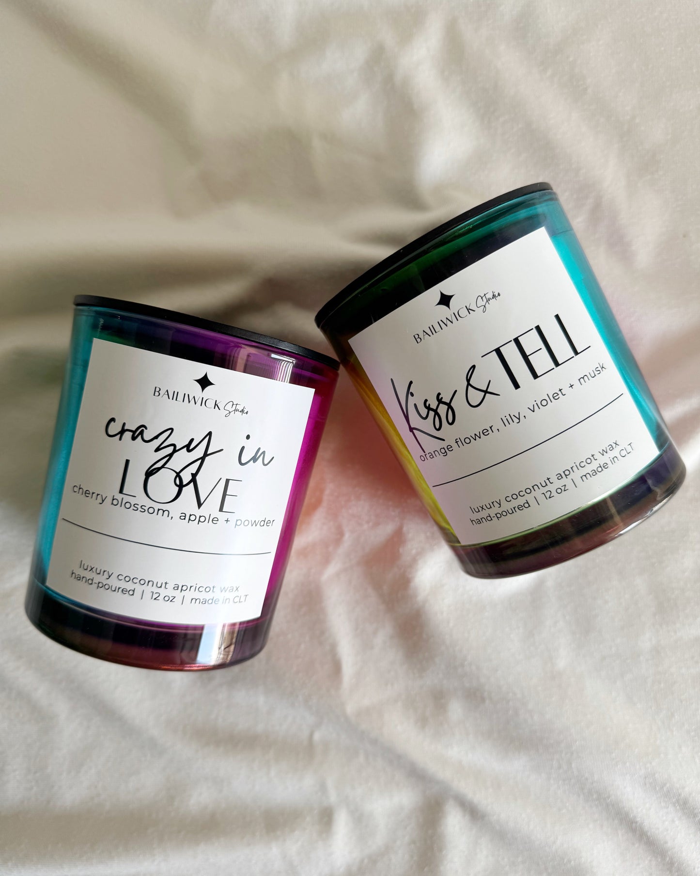 Two candles with labels on a light fabric background