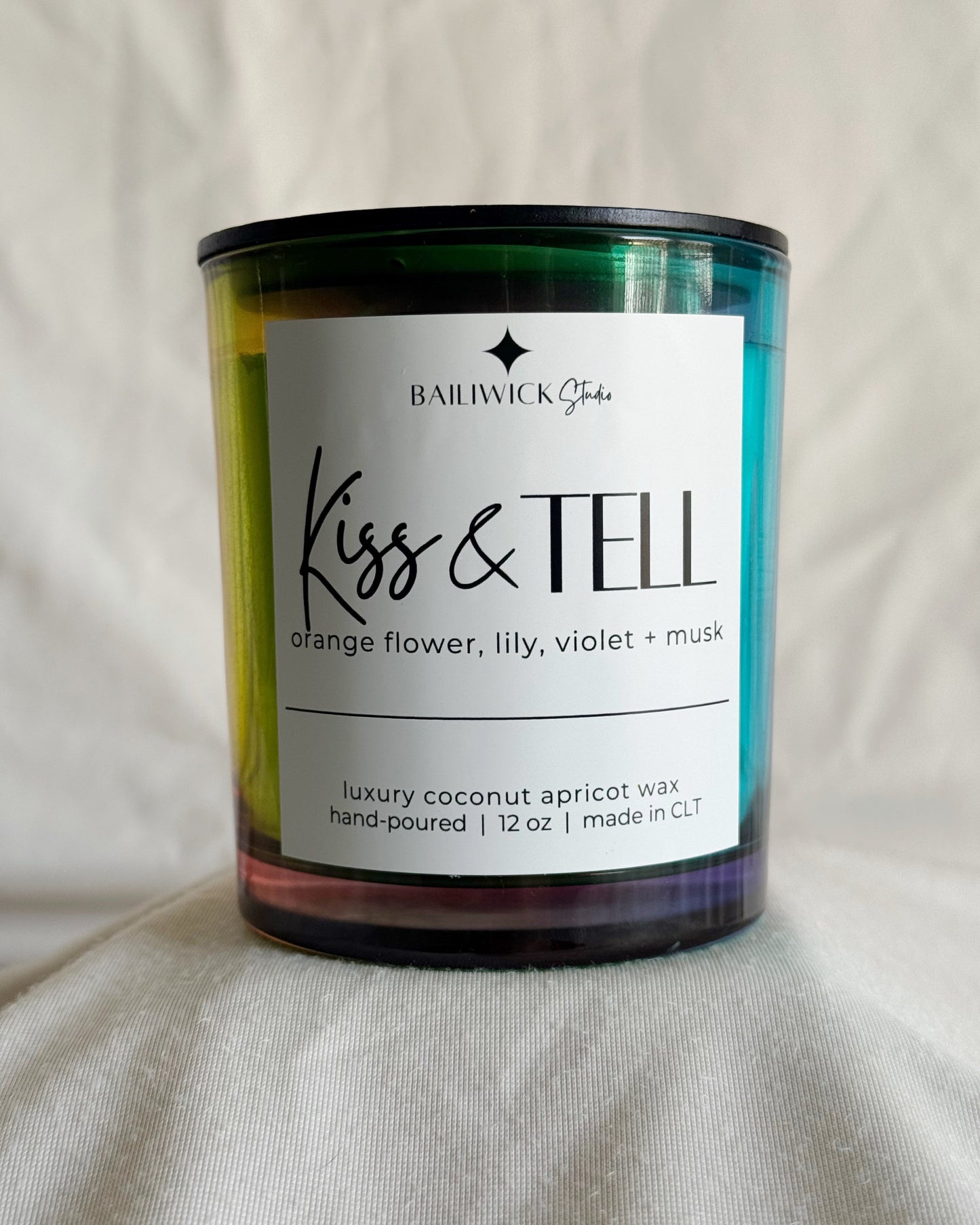 Candle with 'Kiss & Tell' label on a neutral background