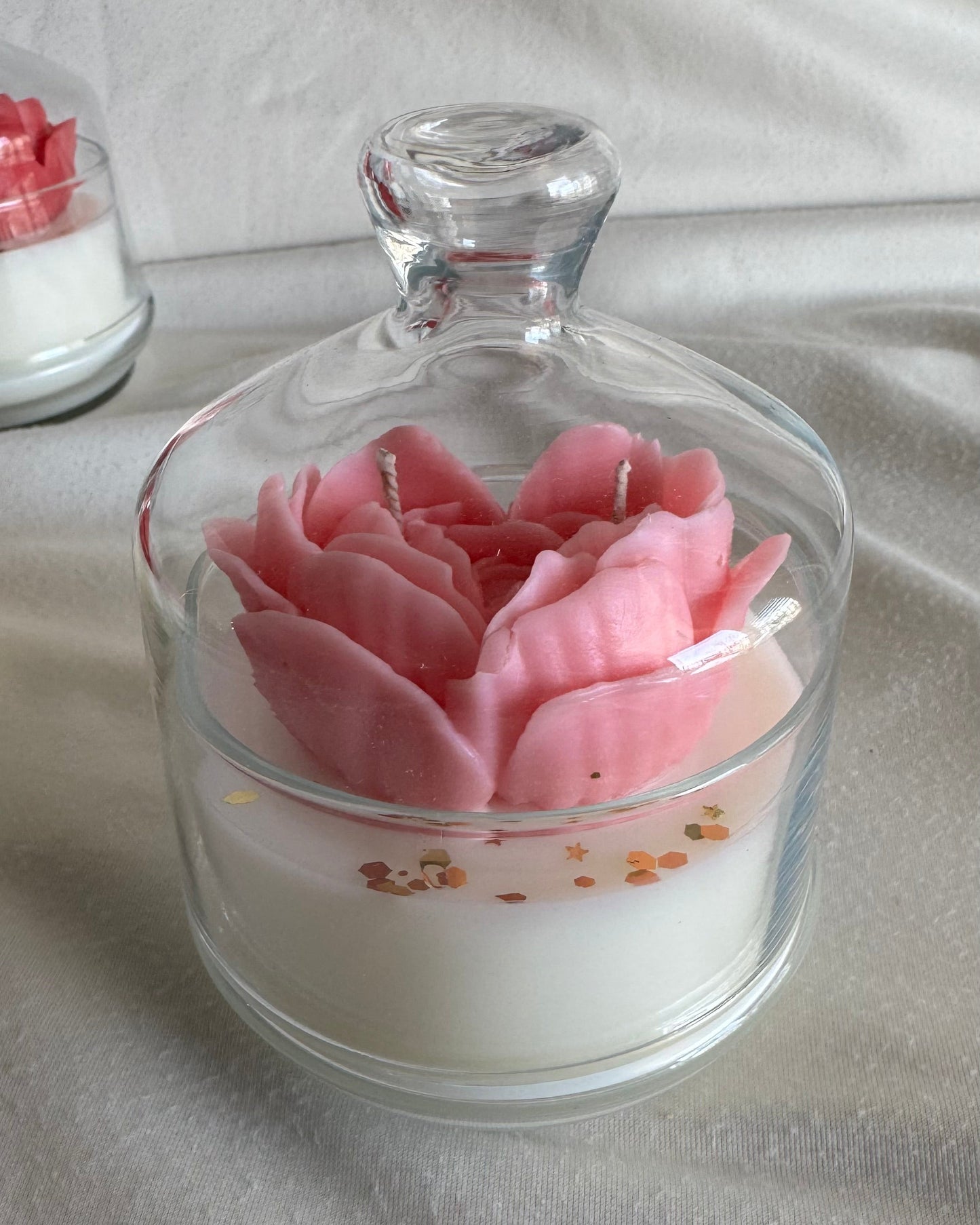 Glass jar with a pink flower inside on a gray surface