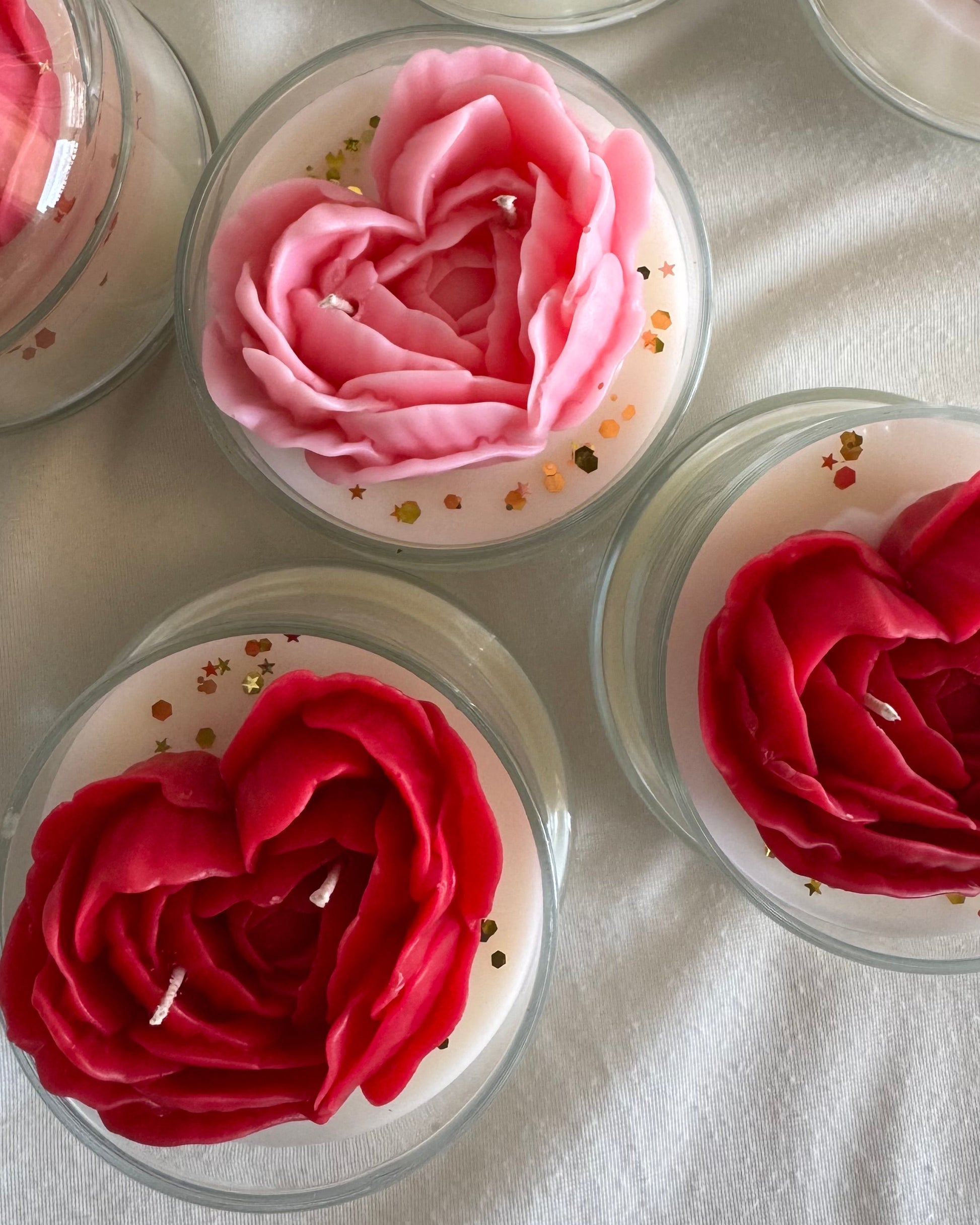 Cupcakes with pink and red rose-shaped candles on a white surface