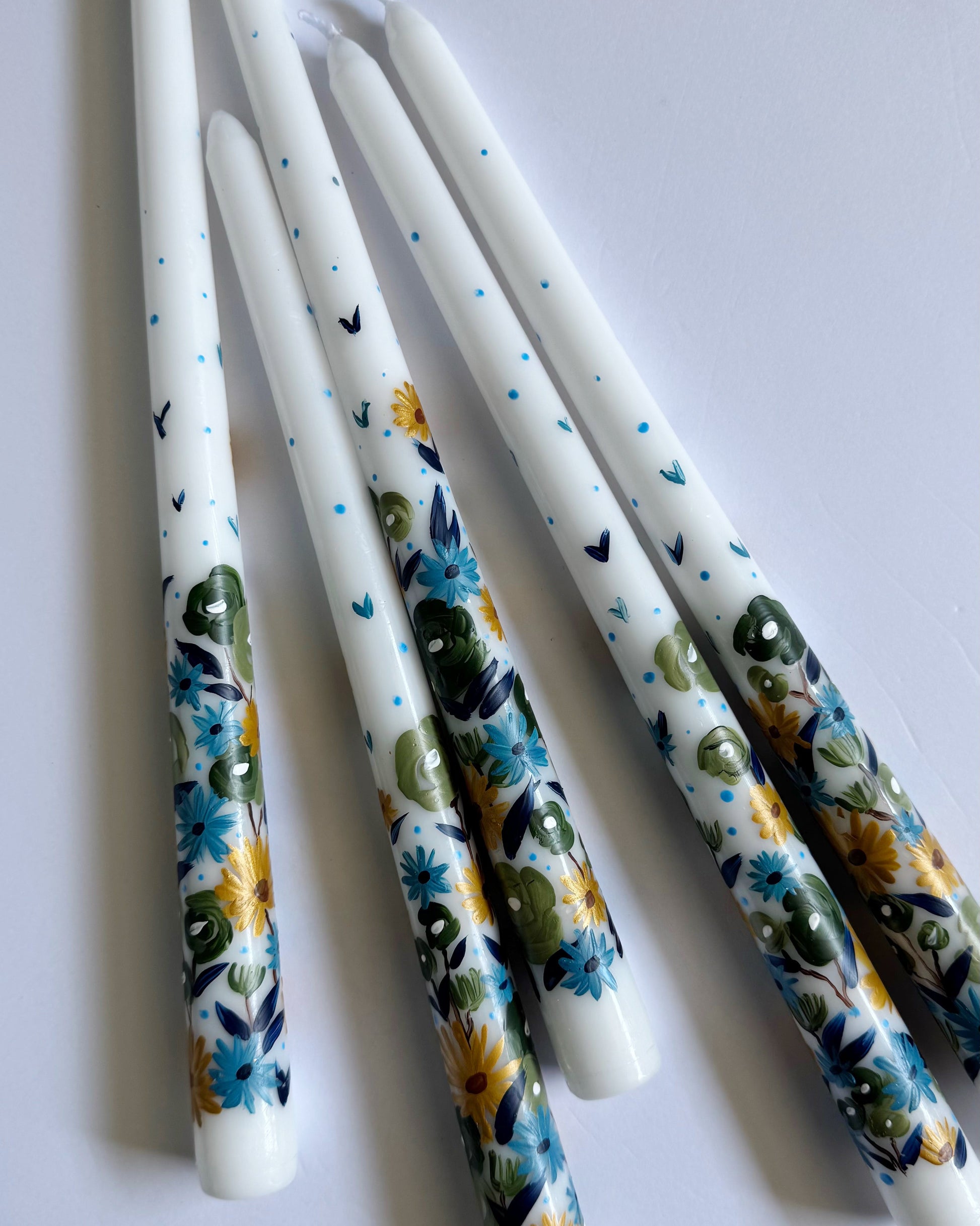 Three hand-painted taper white candles with floral designs 