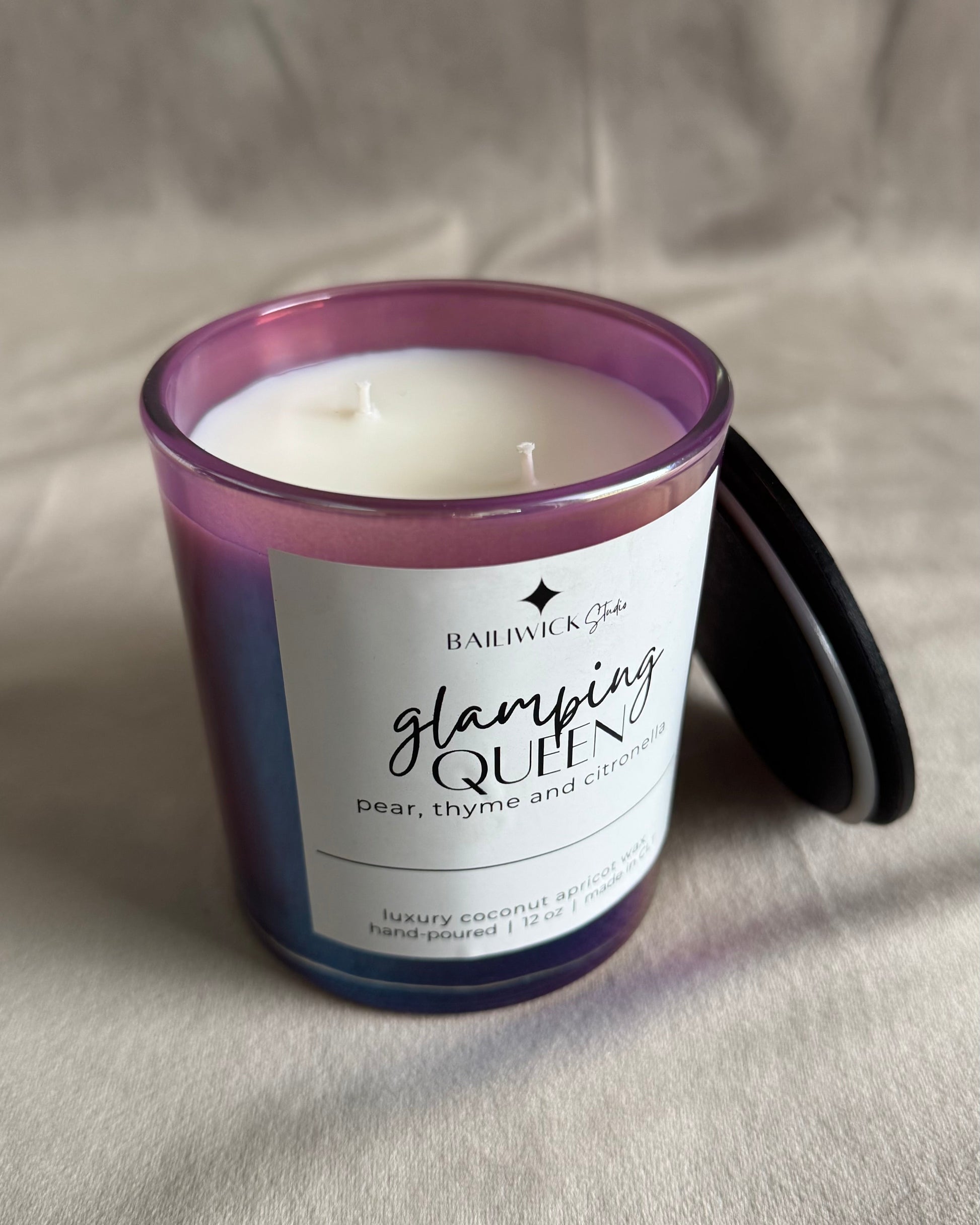 Candle with a purple and white label on a neutral background