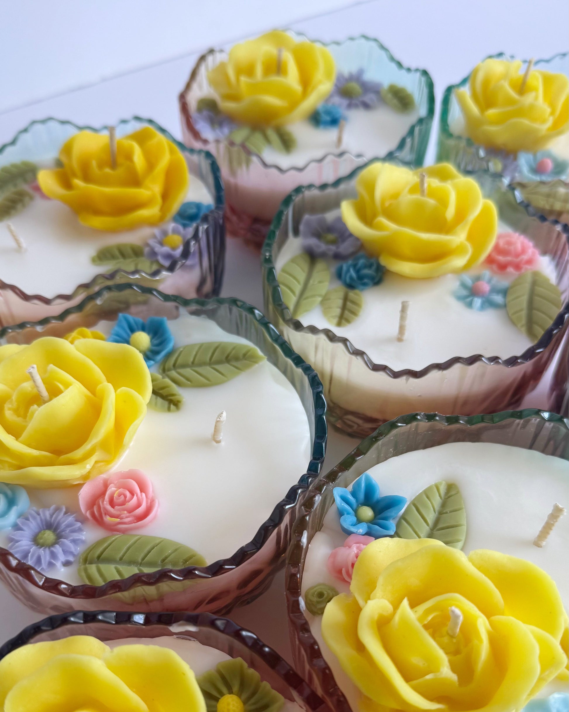 Decorative candles with yellow roses and colorful flowers on a white background