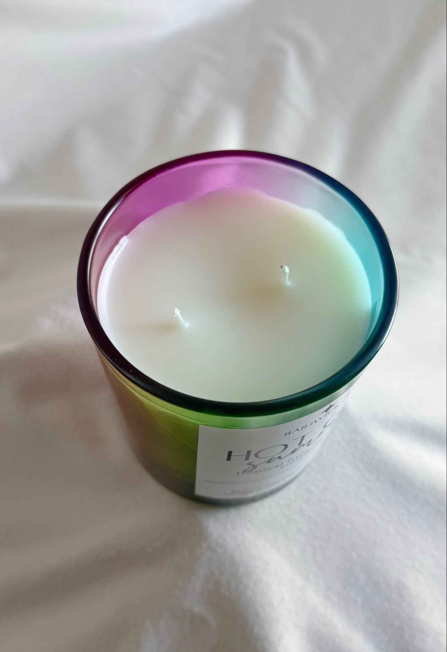 Candle in a colorful container on a white surface