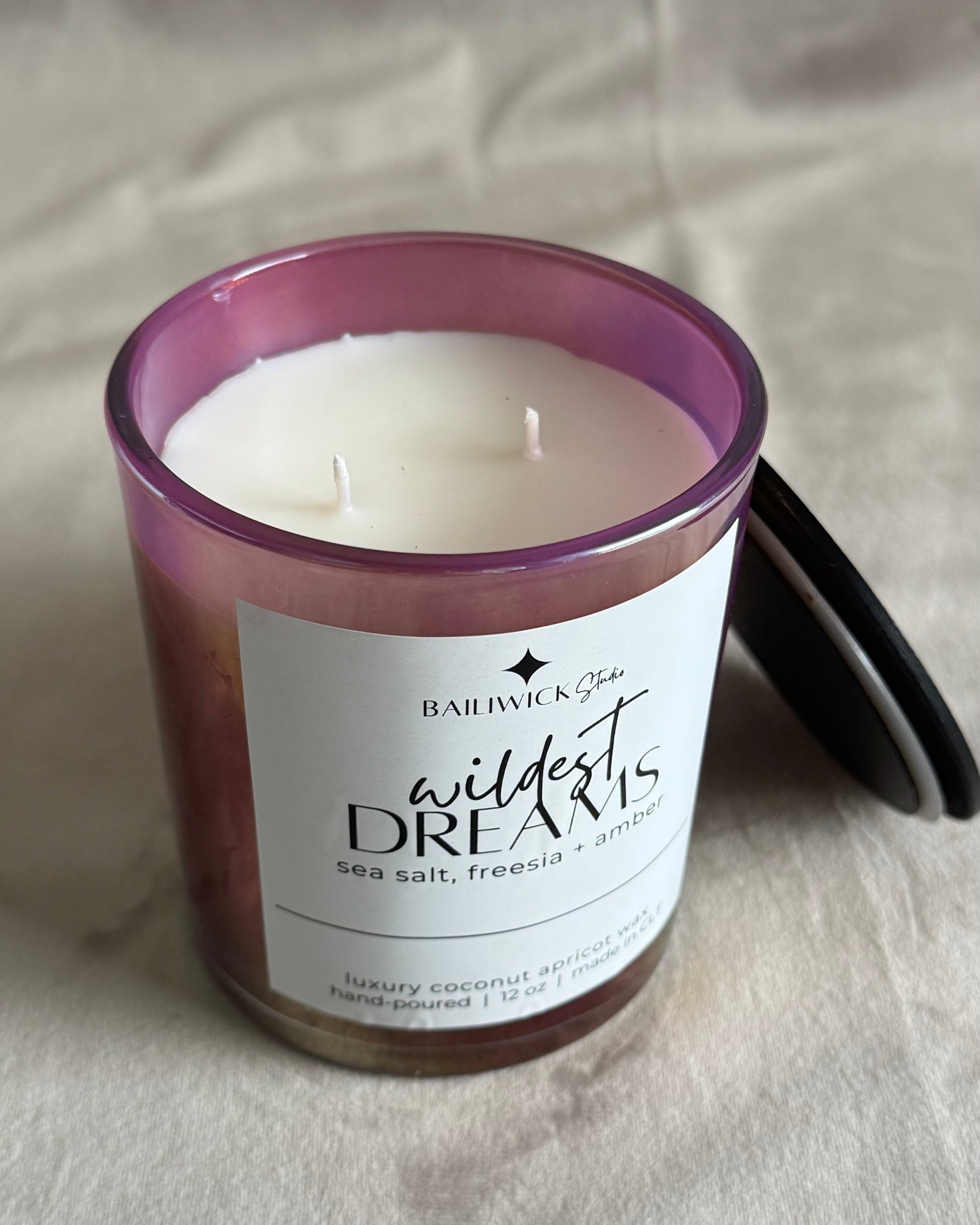 Candle with a purple lid and white label on a neutral background
