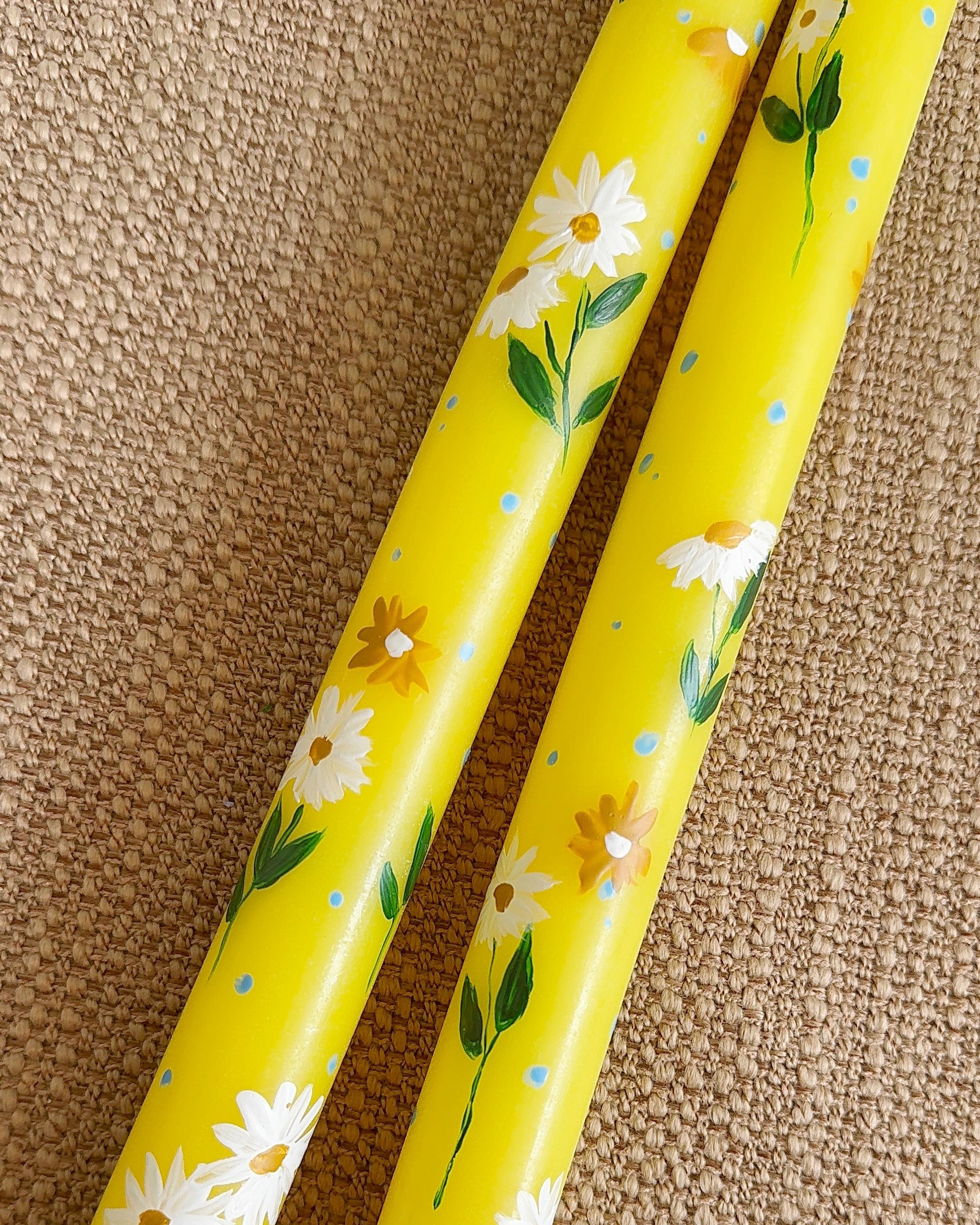 Two yellow sticks with floral pattern on a textured surface